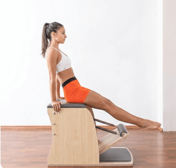 Woman sitting on a Classic Wunda Chair (Pilates equipment)
