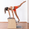 woman performs a Pilates exercise on a light wood Wunda Chair.