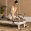 Woman using a Nubium Pilates reformer machine in a home setting.